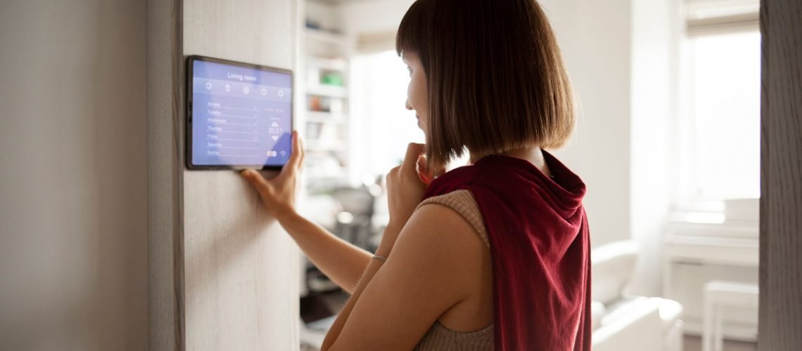 Jeune femme utilisant un appareil pour contrôler à distance les équipements de la maison
